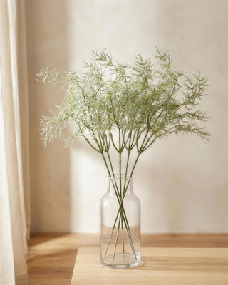 Six artificial rosemary sprays in a clear glass vase on a side table; vase not included