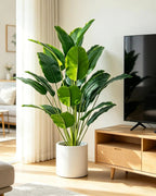 Artificial bird of paradise plant beside a wooden TV console in a living room
