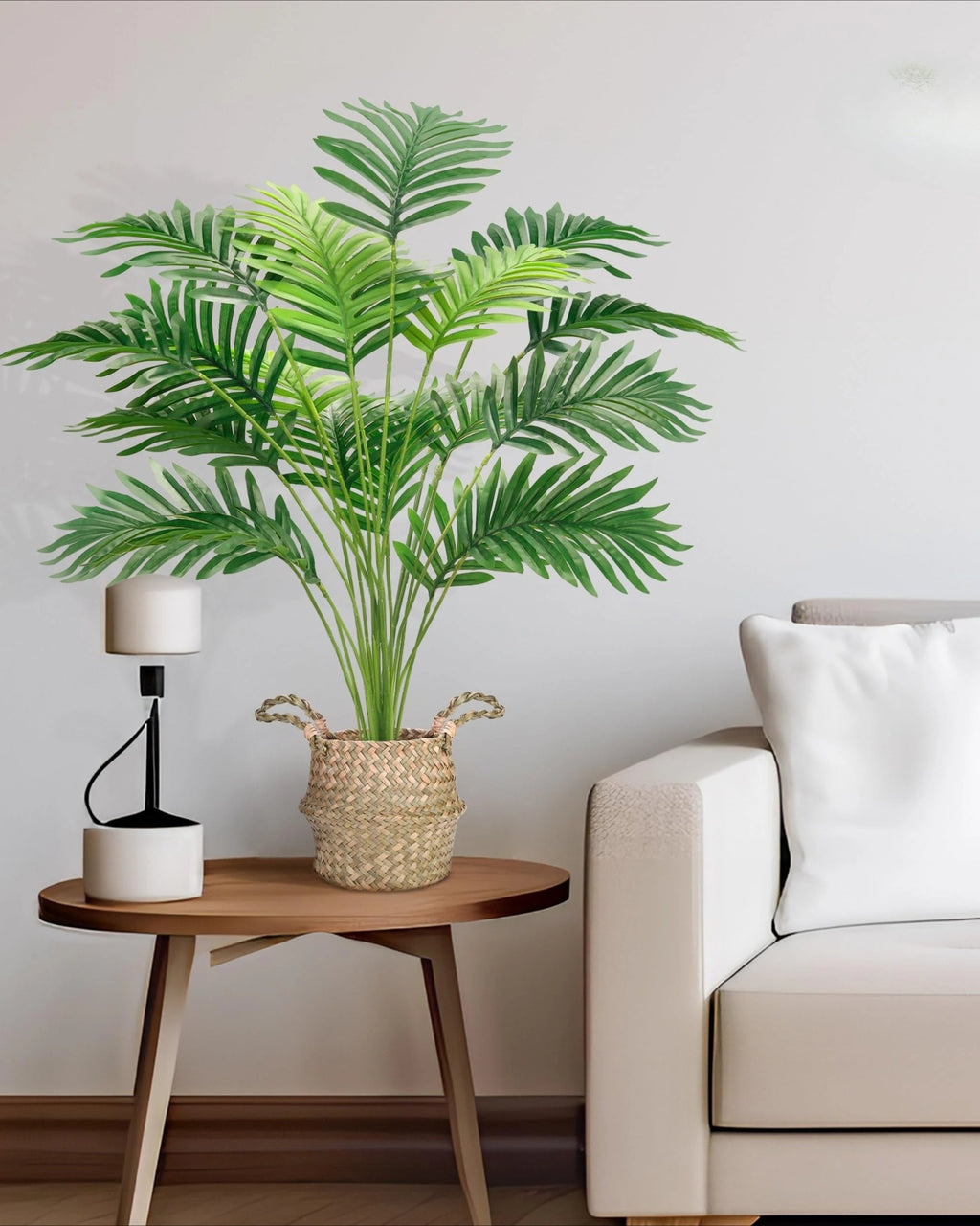 Artificial areca palm in a woven basket on a side table beside a cream sofa