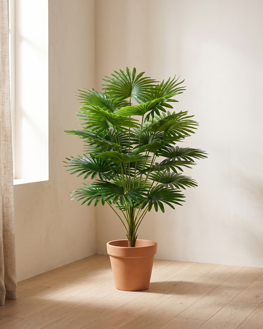 The artificial fan palm in the corner of a bare room, shown in a plain terracotta pot (pot not included).