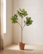 The artificial ficus branch in the corner of a bare room, shown in a plain terracotta pot (pot not included).