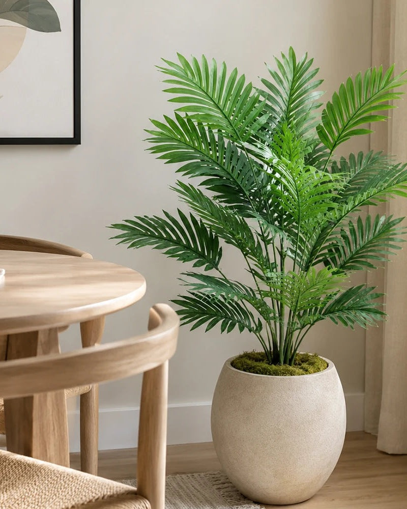 Artificial areca palm in a pale planter next to a wooden dining table