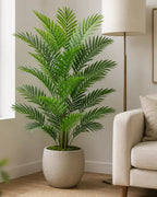 Artificial areca palm in a stone planter beside a sofa in a bright living room