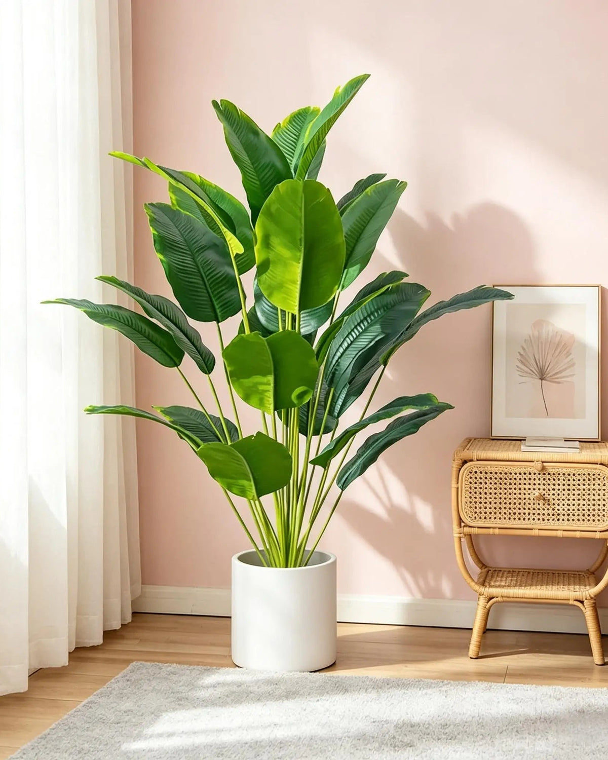 Artificial bird of paradise plant in a white pot against a soft pink wall
