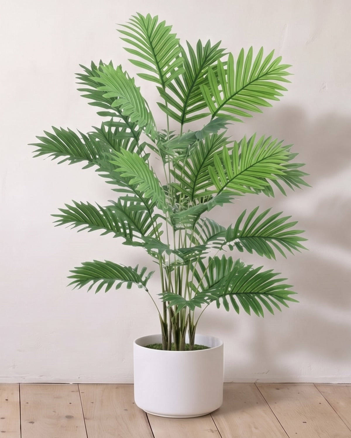 An artificial areca palm with eighteen fronds, 32 in tall, in a plain white pot against a warm white wall; pot not included