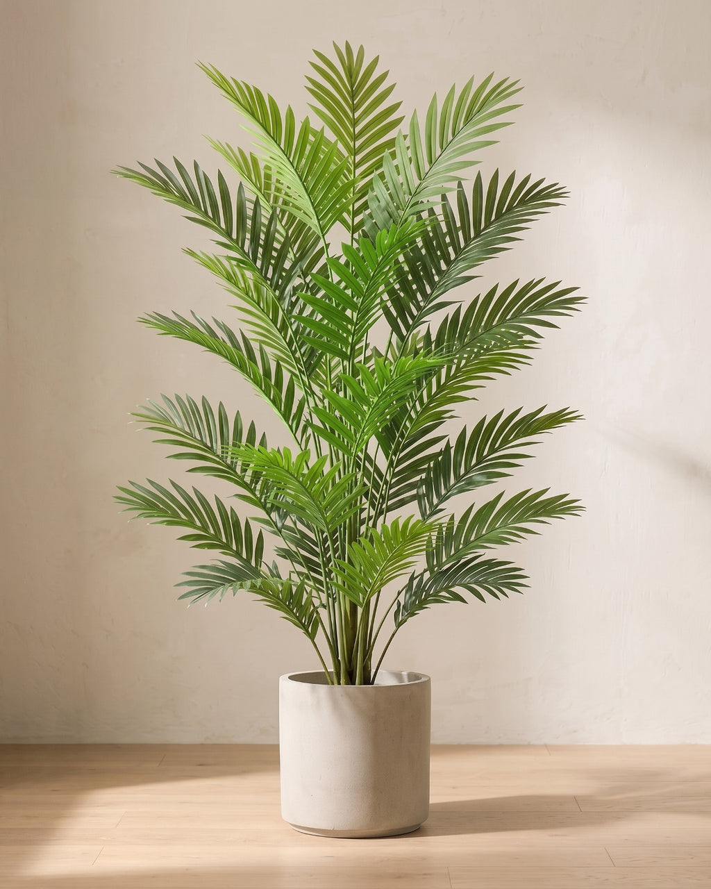An artificial areca palm with eighteen fronds, in a plain stone pot on an oak floor; pot not included