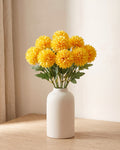 Golden Yellow artificial pompom chrysanthemums standing in a vase on a pale oak table; no vase is included