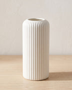White striped cylinder vase, empty on a pale oak table