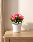 A small artificial flowering pot with bright pink blooms, in the white pot it comes in, on a pale oak table
