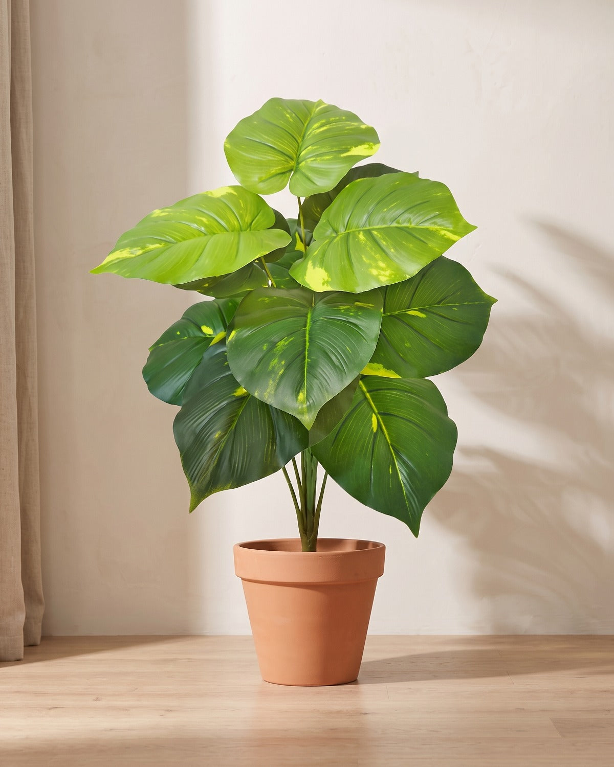 Artificial leaf bush with whole rounded leaves blotched yellow-green over deep green, in a plain terracotta pot; pot not included
