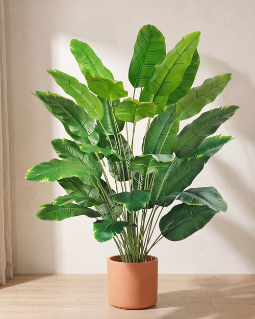 Green leaf artificial banana leaf plant in a plain terracotta pot on pale oak floorboards; pot not included