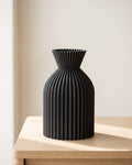 Black ribbed bottle vase, small, empty on a pale oak table