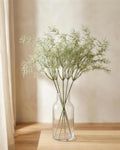 Six artificial rosemary sprays in a clear glass vase on a side table; vase not included