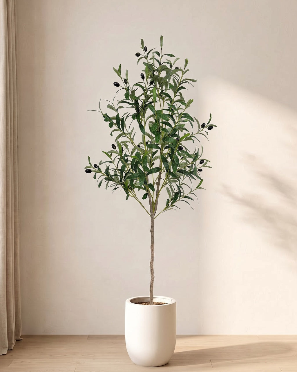 The 47 in artificial olive tree, the slimmest of the set, standing in a plain white pot on an oak floor; planter not included