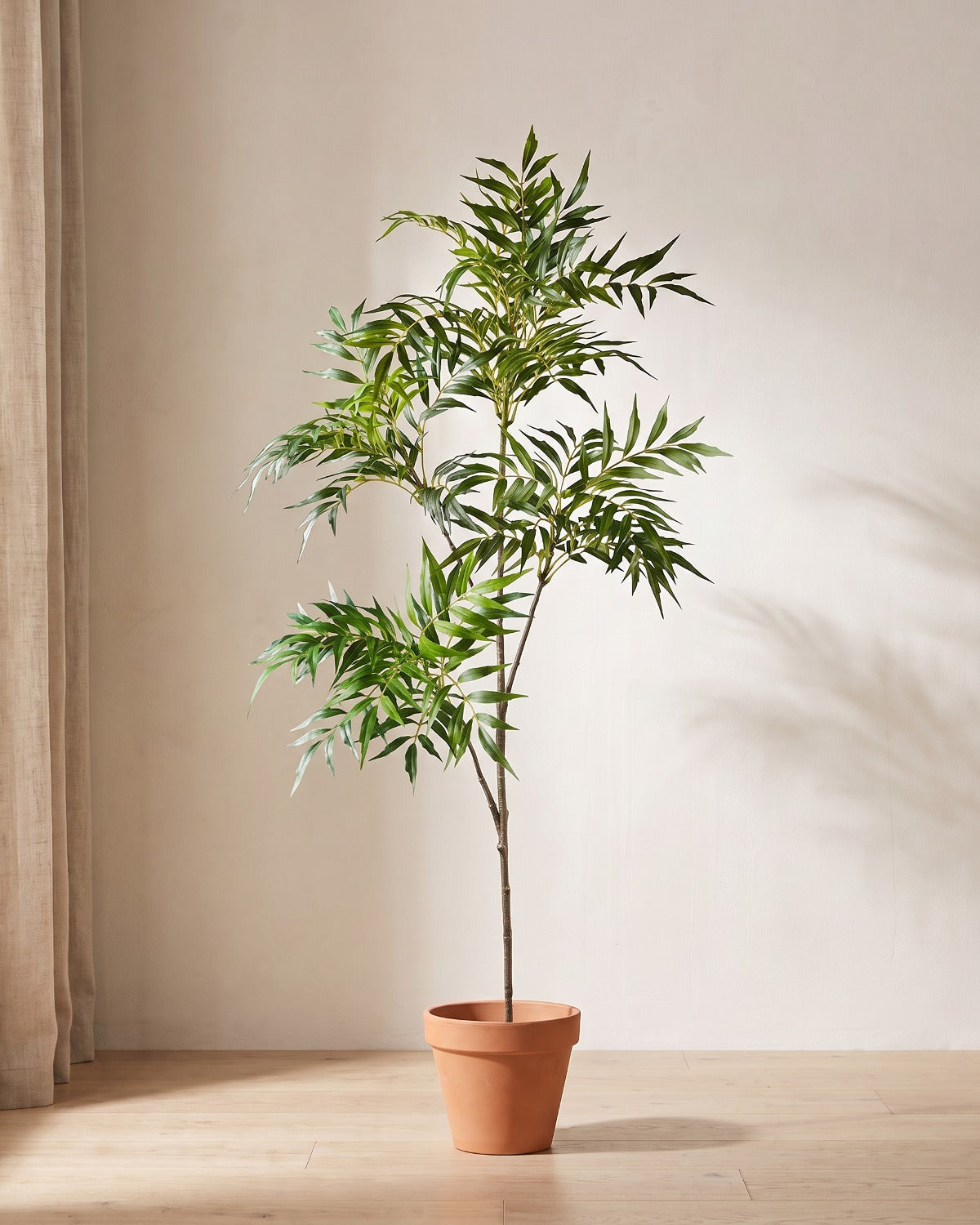 Artificial bamboo branch with two side branches standing in a plain terracotta pot on pale oak floorboards (pot not included).