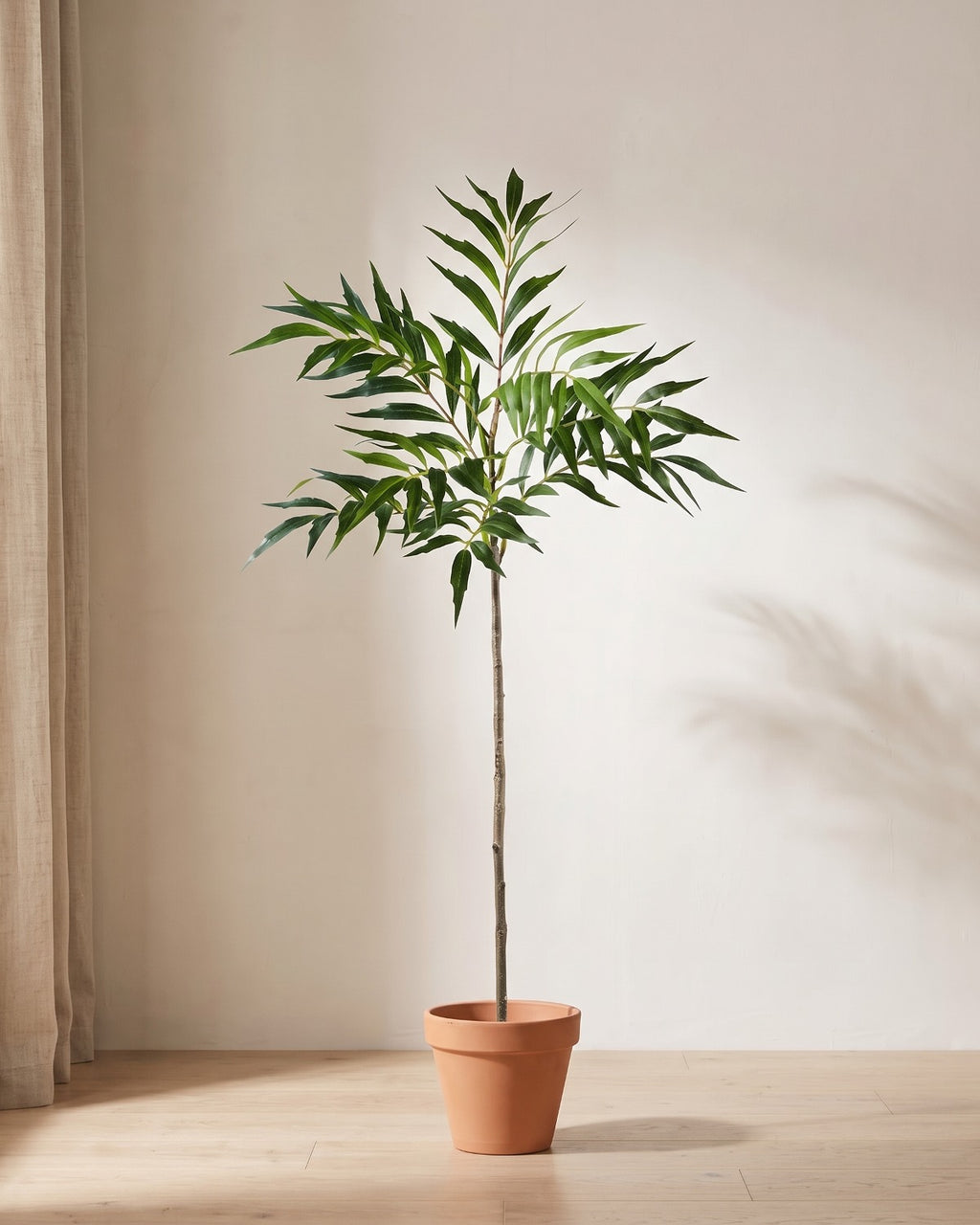 Artificial bamboo branch, a single stem, standing in a plain terracotta pot on pale oak floorboards (pot not included).