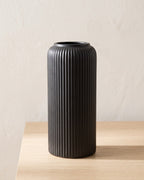 Black striped cylinder vase, empty on a pale oak table