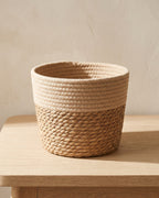 Woven seagrass plant basket, size M, empty on a pale oak table