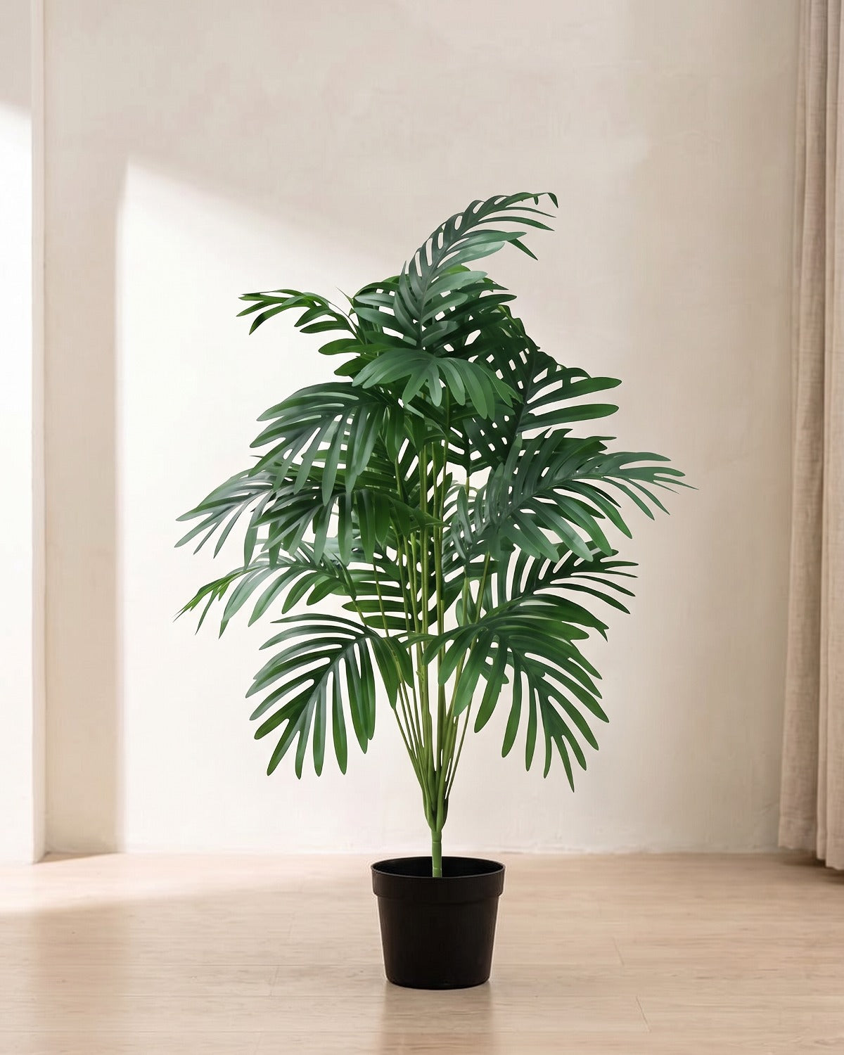 An artificial palm leaf bush with eighteen fronds in a plain black nursery pot on pale oak floorboards in a bright room; pot not included
