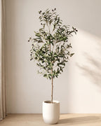 The 55 in artificial olive tree standing in a plain white pot on an oak floor; planter not included