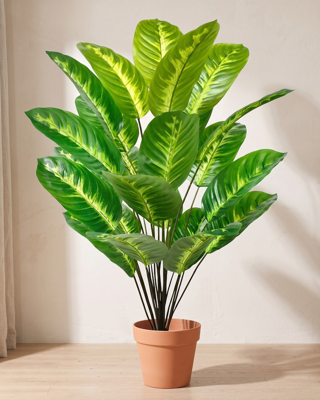 Variegated leaf artificial banana leaf plant in a plain terracotta pot on pale oak floorboards; pot not included