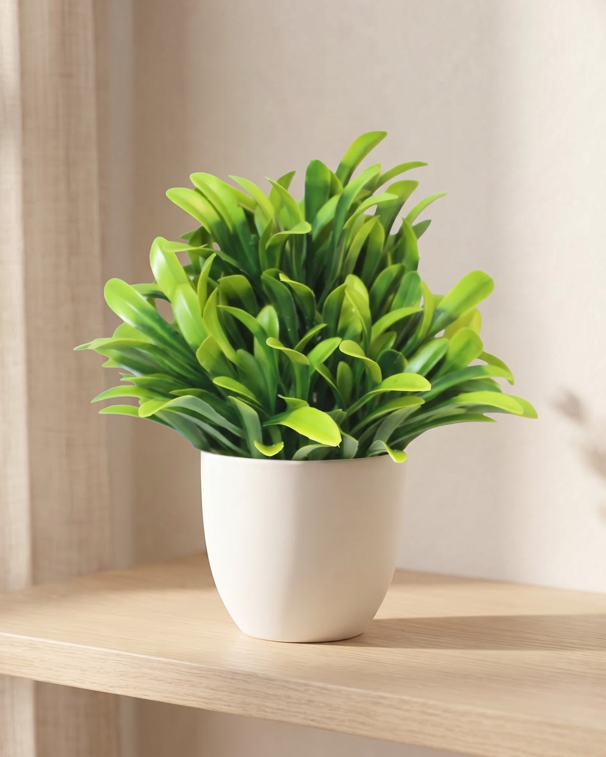 Peperomia style mini artificial potted plant in a plain white pot on a pale oak table