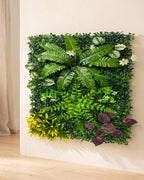 Fern, yellow bloom and purple artificial green wall panel fixed flat on an off-white plaster wall