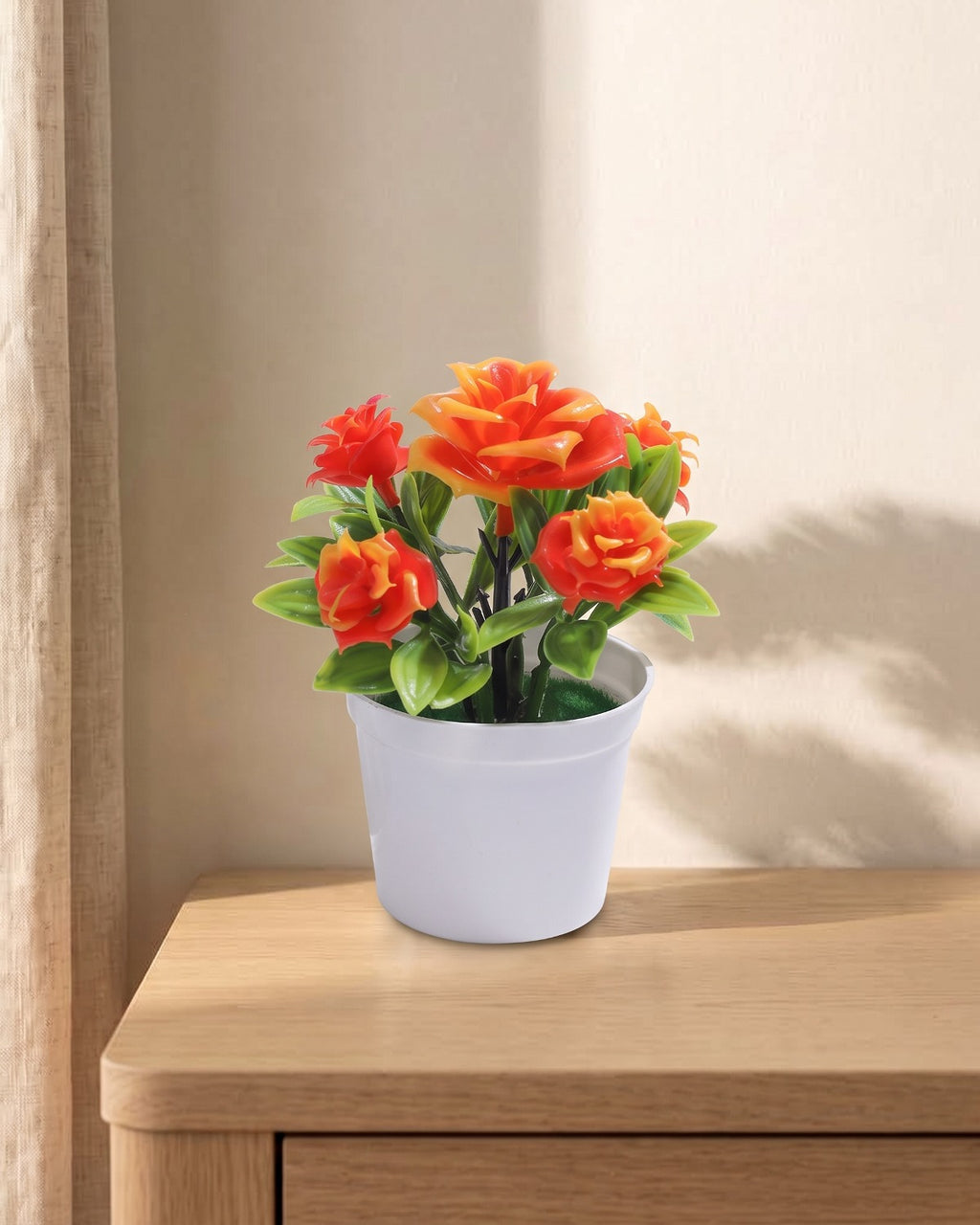 A small artificial flowering pot with orange blooms, in the white pot it comes in, on a pale oak table