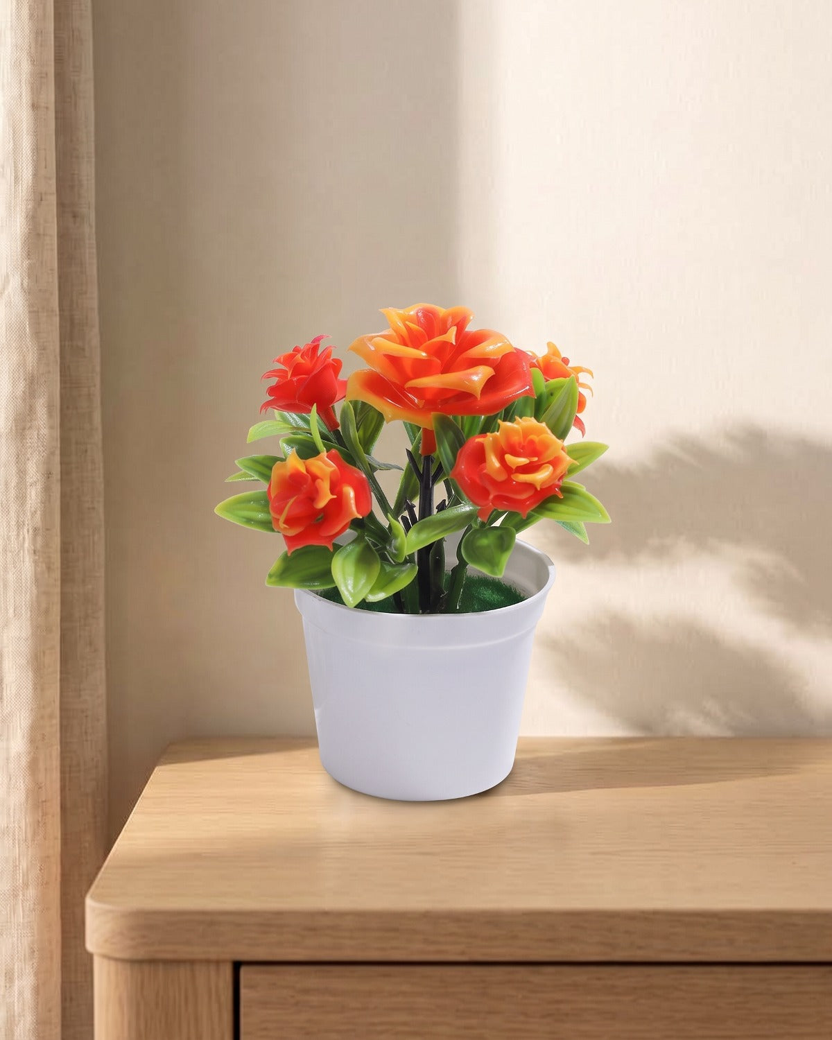 A small artificial flowering pot with orange blooms, in the white pot it comes in, on a pale oak table