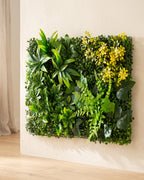 An artificial green wall panel fixed flat to a pale plaster wall, seen slightly from the side so the depth of the foliage shows
