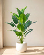 The 36 in artificial bird of paradise with twenty-four leaves, in a plain white pot on an oak floor; pot not included