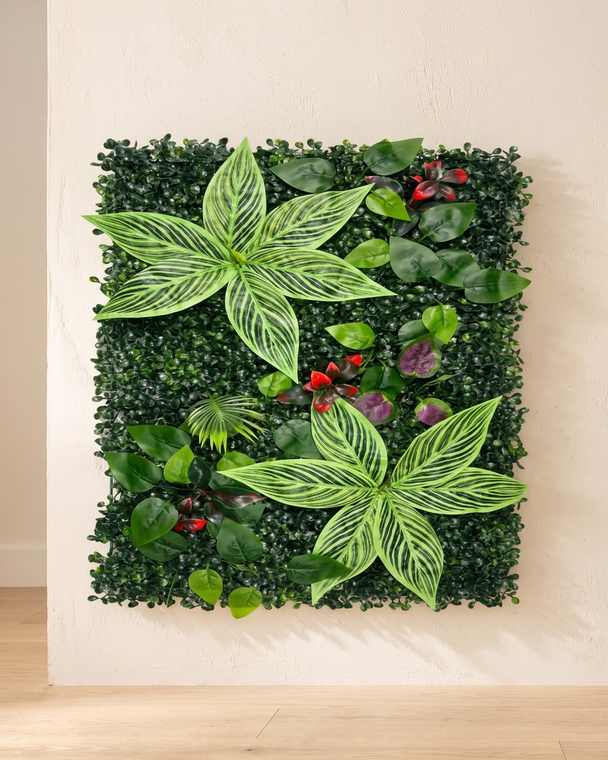 Variegated leaf and red berry artificial green wall panel fixed flat on an off-white plaster wall