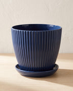 Navy fluted plant pot and saucer, empty on a pale oak table