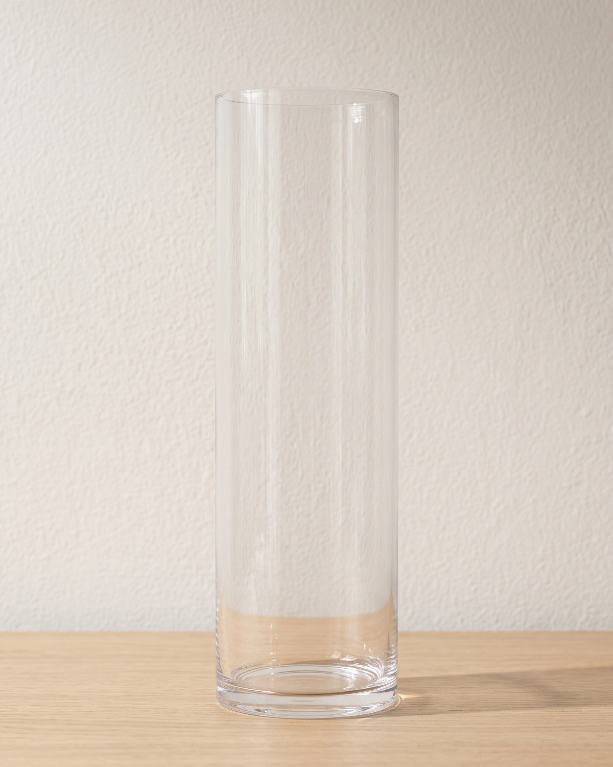 Clear acrylic cylinder vase, size L, empty on a pale oak table