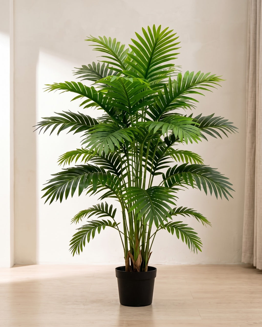 An artificial palm leaf bush with twenty-one fronds in a plain black nursery pot on pale oak floorboards in a bright room; pot not included