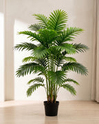 An artificial palm leaf bush with twenty-one fronds in a plain black nursery pot on pale oak floorboards in a bright room; pot not included