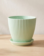 Mint fluted plant pot and saucer, empty on a pale oak table