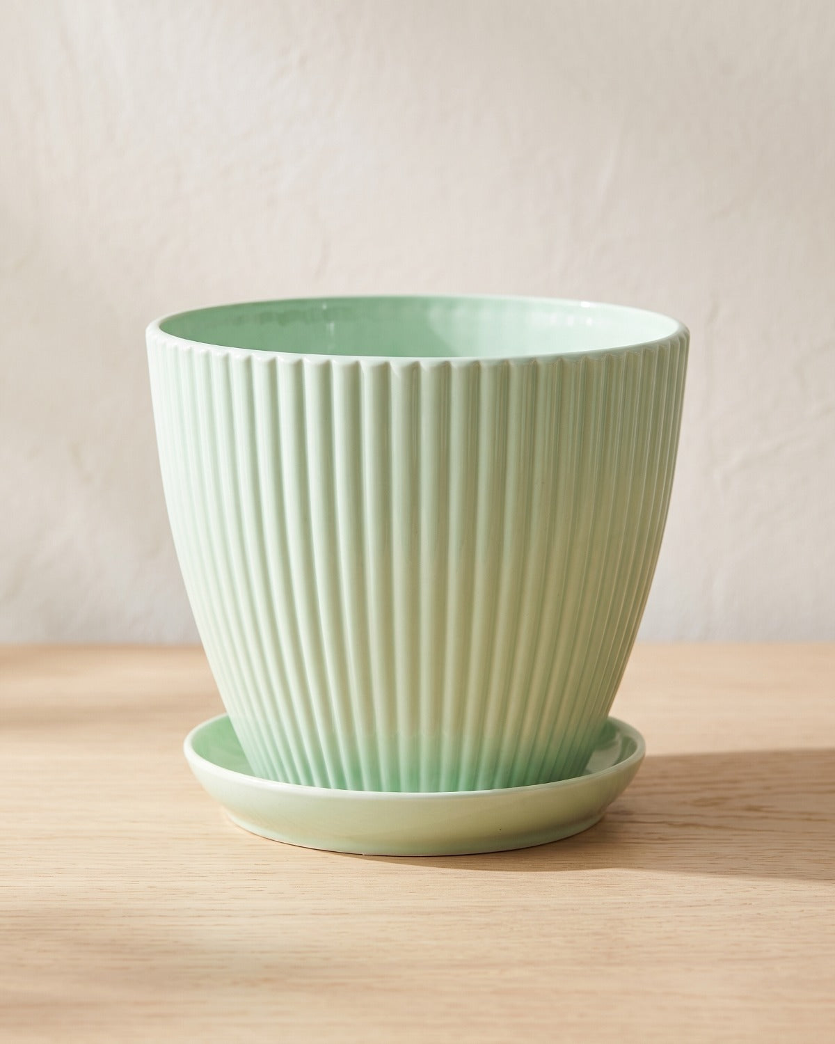 Mint fluted plant pot and saucer, empty on a pale oak table