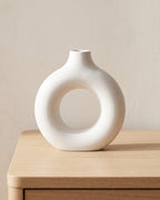 White donut vase, small, empty on a pale oak table