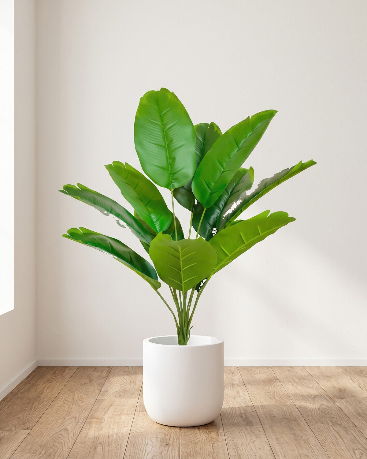 The 26 in artificial bird of paradise with twelve leaves, in a plain white pot on an oak floor; pot not included