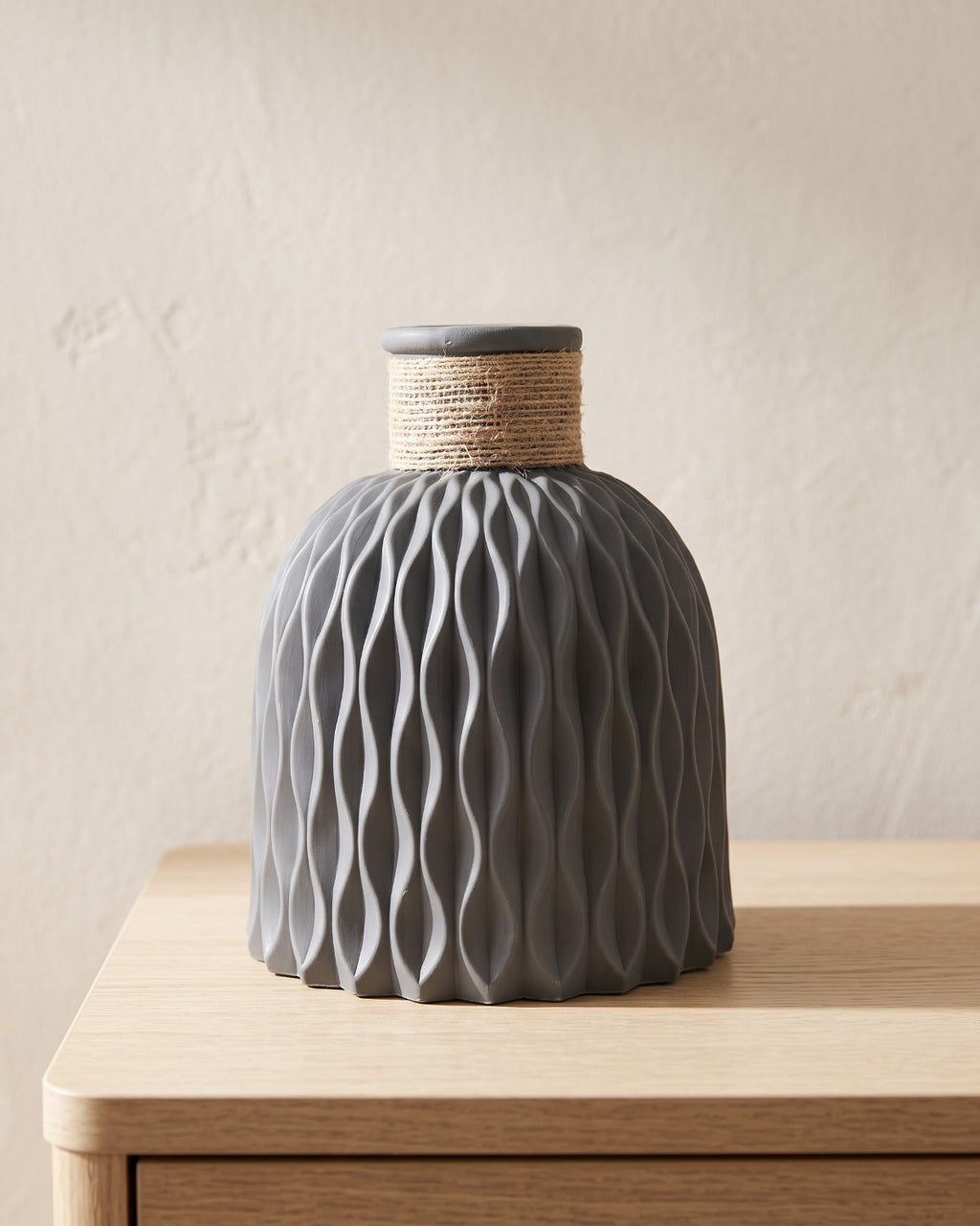Dark gray rope neck vase, empty on a pale oak table