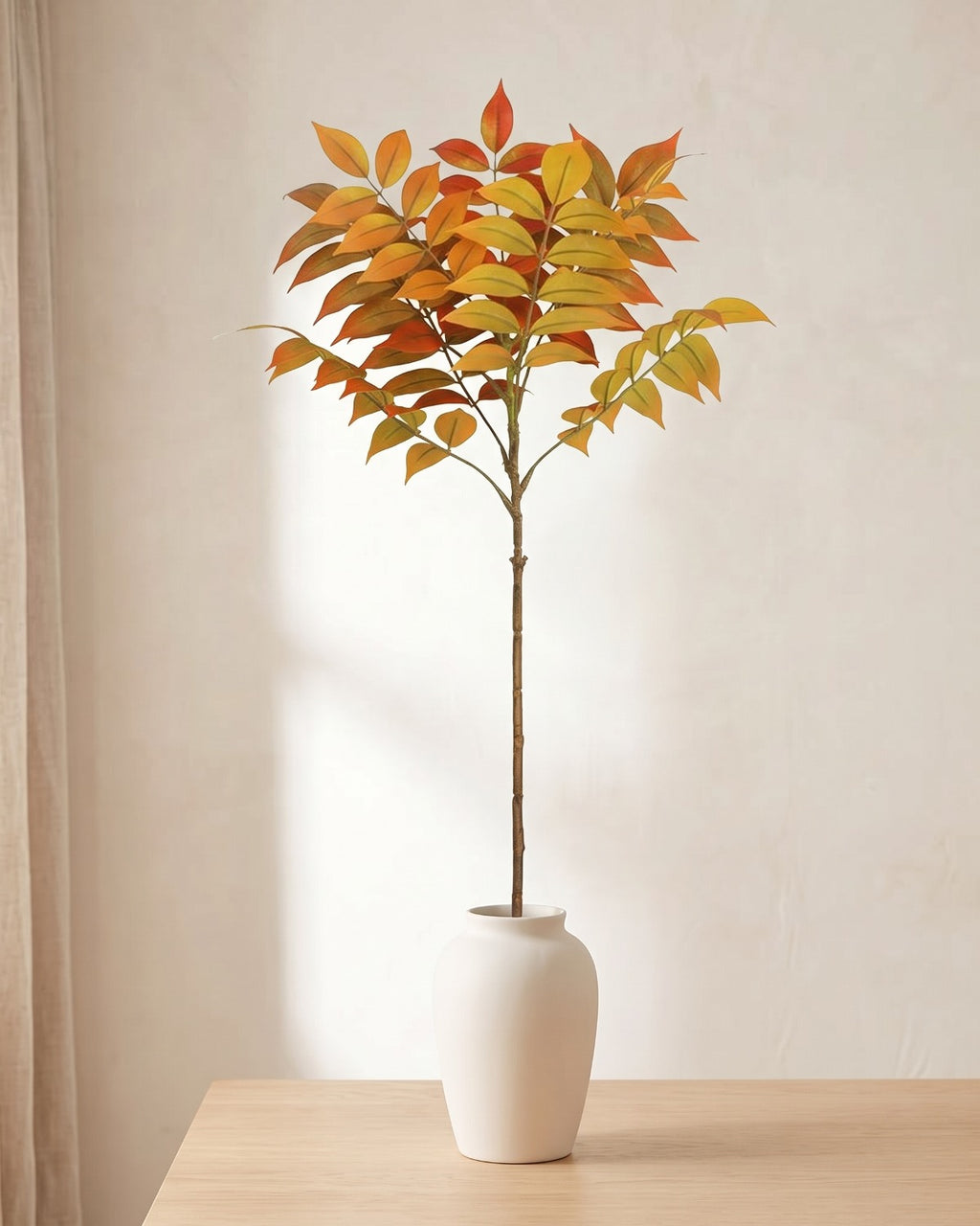 Autumn leaf artificial tree branch standing in a plain off-white vase on a pale oak table; no vase is included