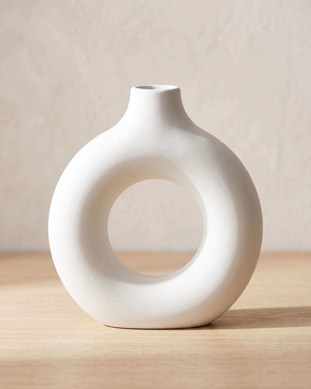 White donut vase, medium, empty on a pale oak table
