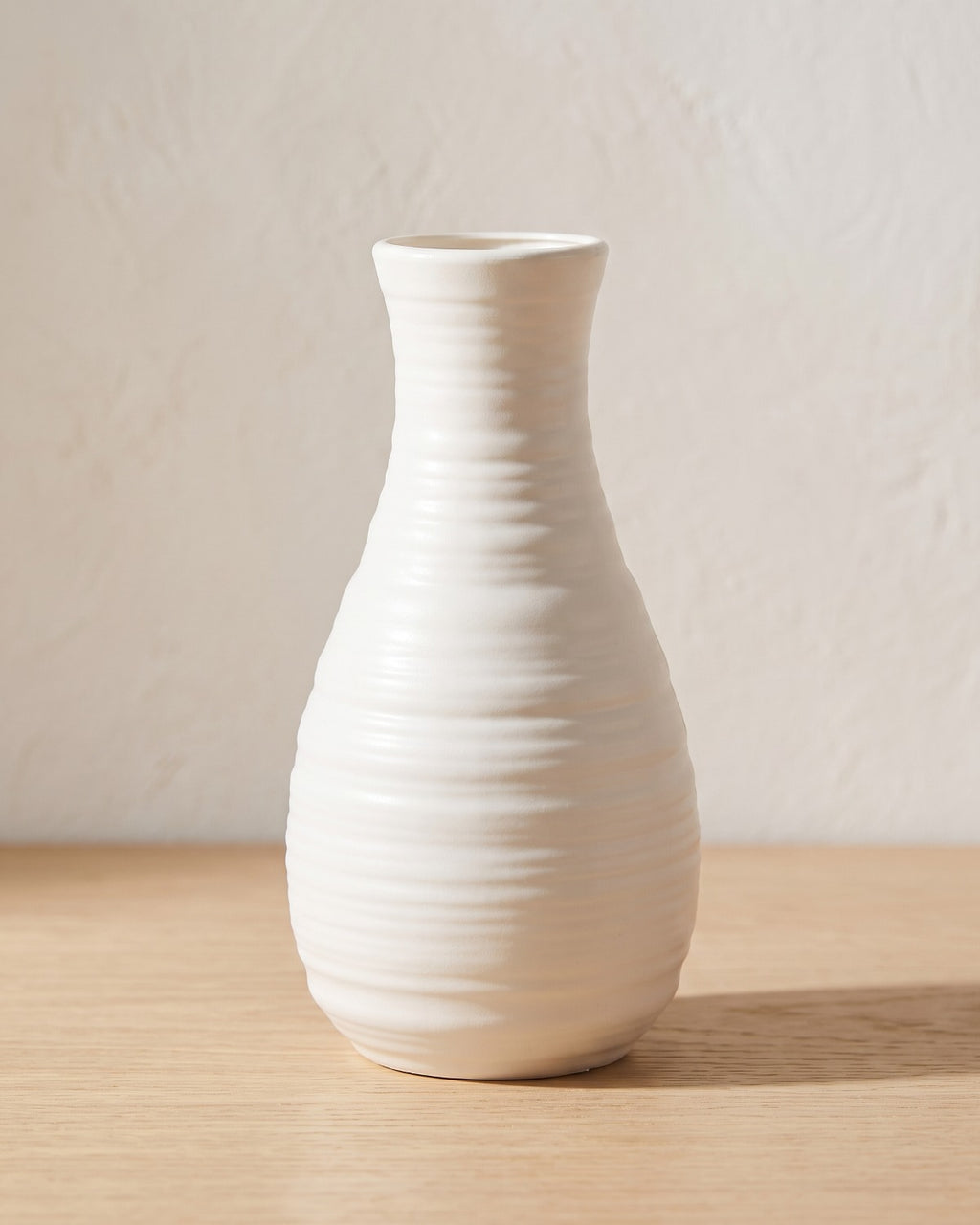 Ribbed bottle origami vase, 8.1 in, empty on a pale oak table