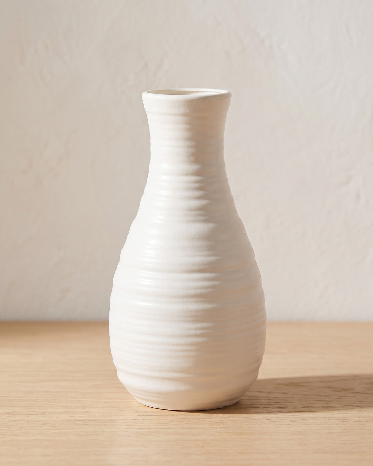 Ribbed bottle origami vase, 8.1 in, empty on a pale oak table