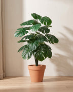 Artificial monstera bush with deeply split leaves in plain deep green, in a plain terracotta pot; pot not included