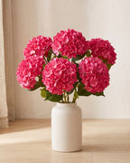 Rose Red artificial hydrangea flowers standing in a plain off-white vase on a pale oak table; no vase is included