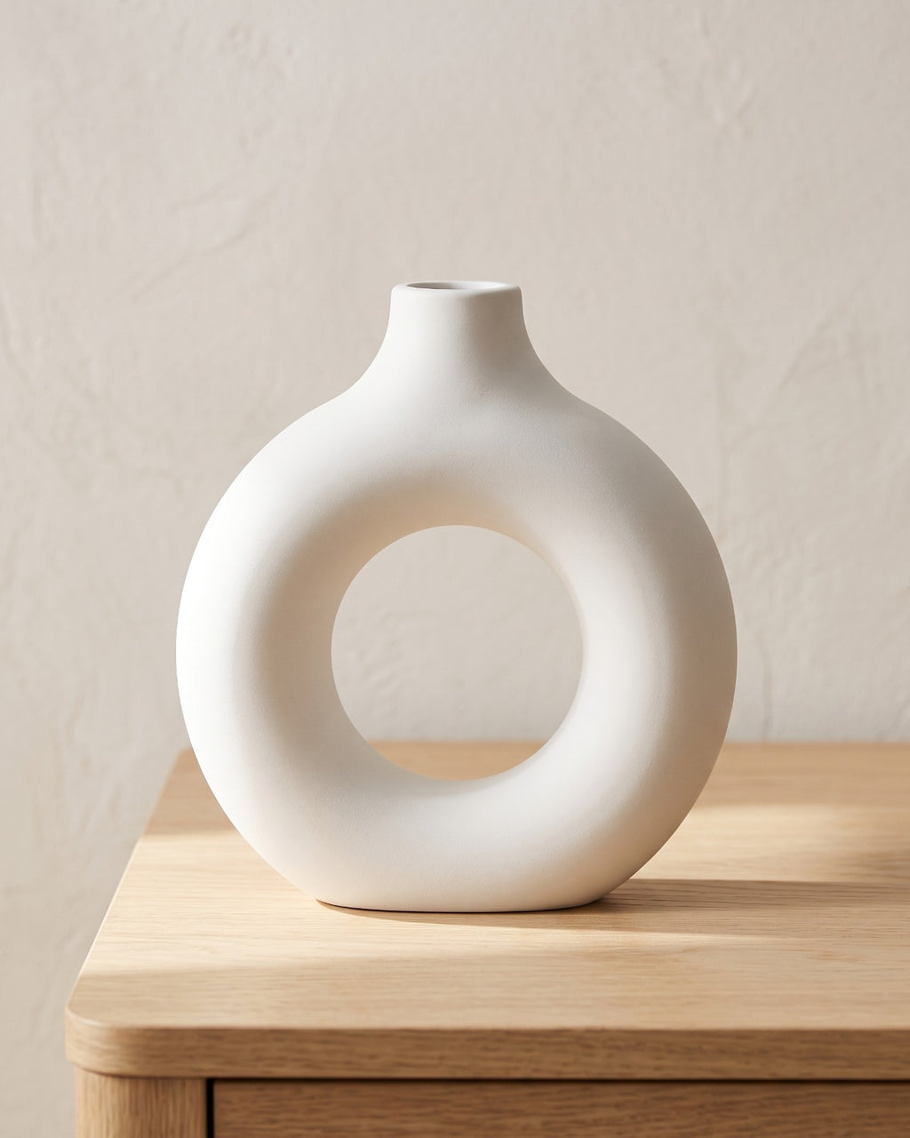 White donut vase, large, empty on a pale oak table
