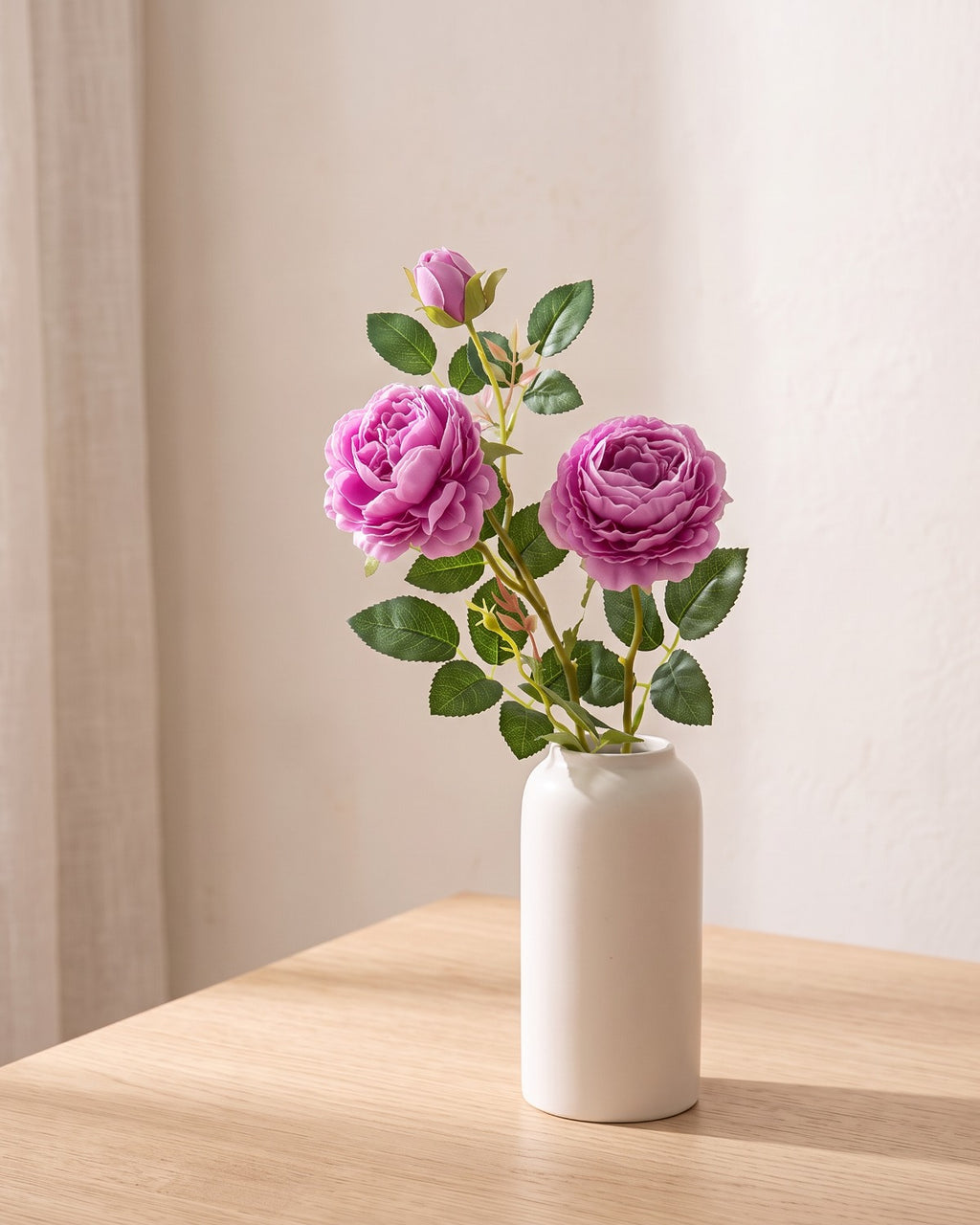 Purple artificial rose branch standing in a plain off-white vase on a pale oak table; each order is one branch, and no vase is included