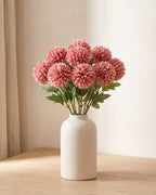 Dusty Rose artificial pompom chrysanthemums standing in a vase on a pale oak table; no vase is included